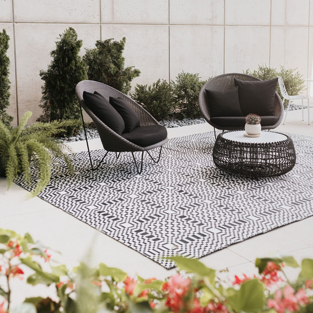 Black and white rug with geometric design and chairs on outdoor patio
