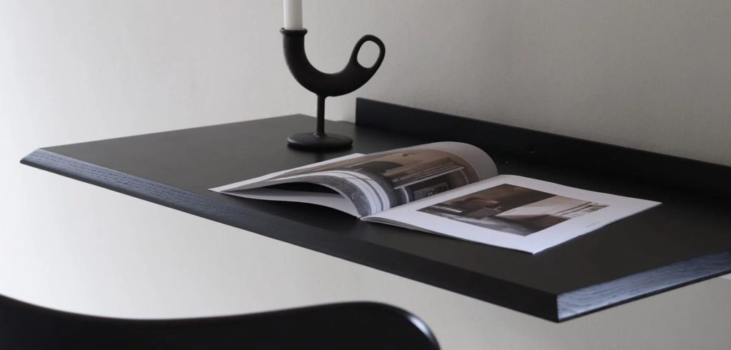 Black floating desk with magazine and candle