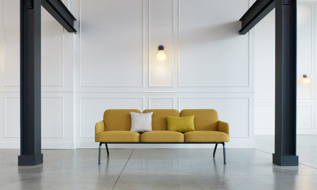 Nordic three-seater in yellow in room with large steel beams and posts