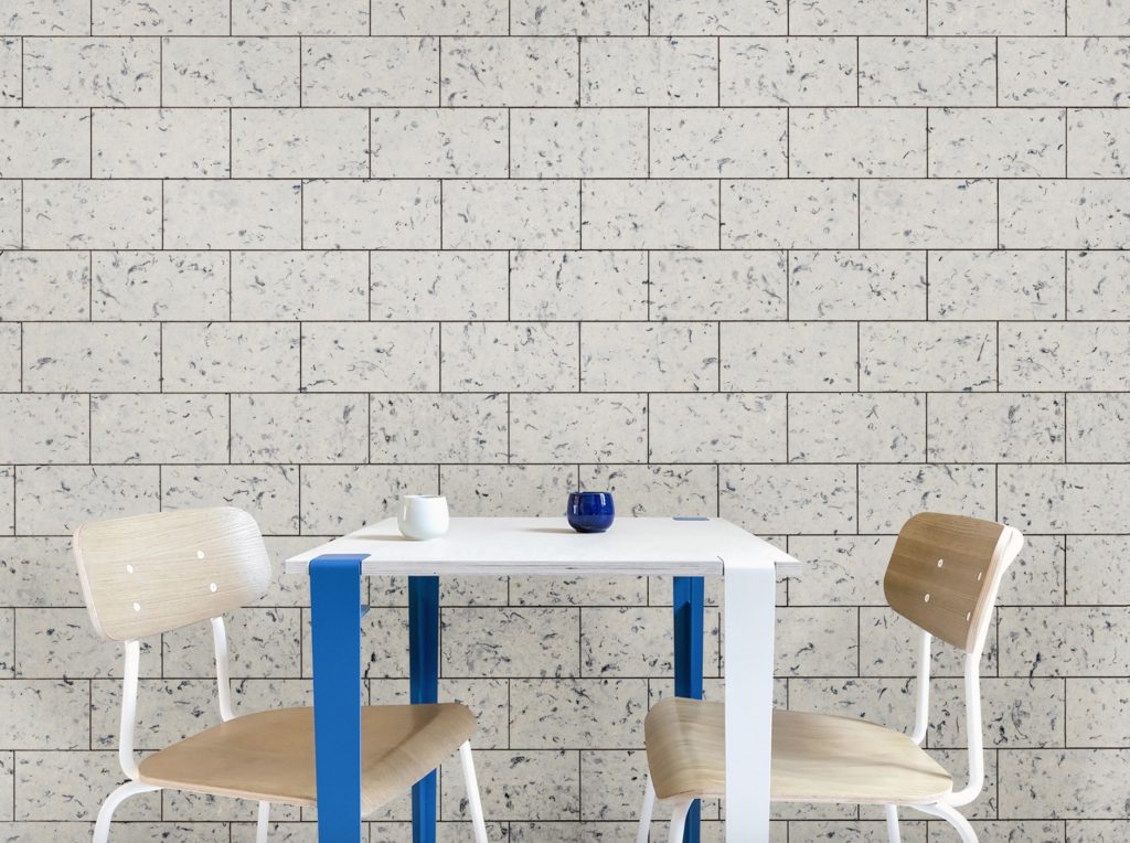 Pierreplume wall panel formed into brick like shapes and covering entire wall with table in front in speckled white