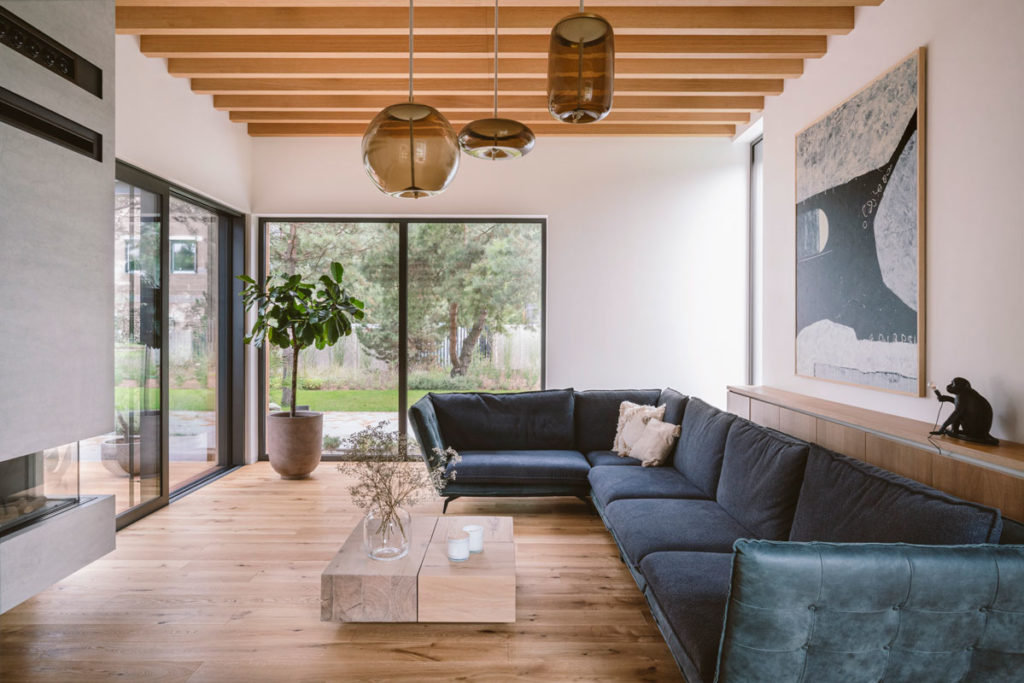 Boho house living room with large blue sectional sofa, wood floors, and nice view at trees outside