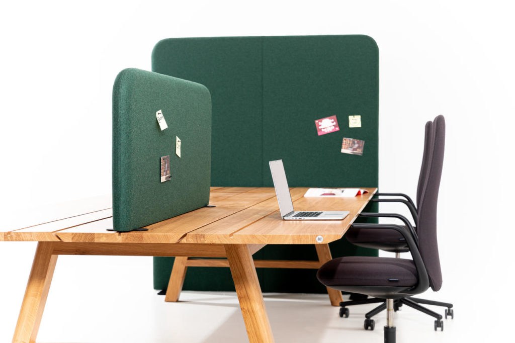 Green space divider and green desk partition on wooden desk with computer and two brown task chairs