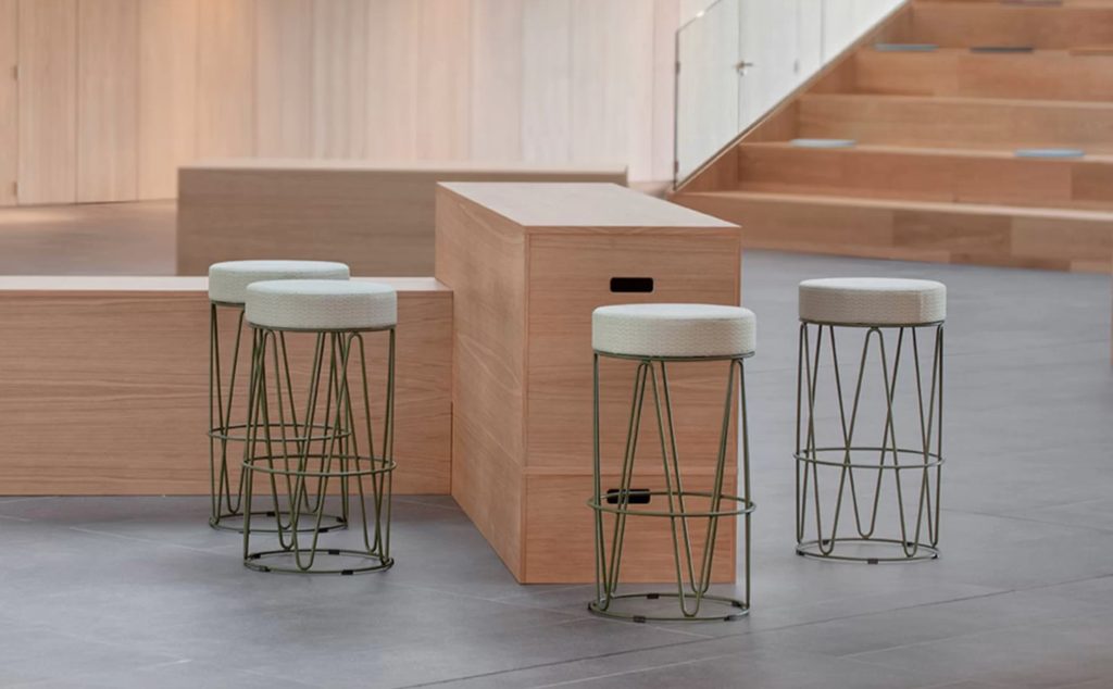 Four stools in lobby/vestibule with wood stairs and wooden bar/standing work surface