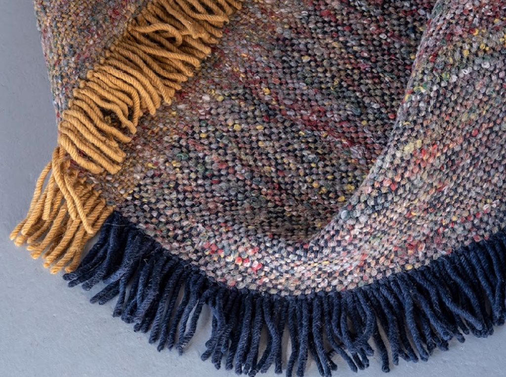 Re-rug detail with many colors iin speckled effect and yellow and blue fringe