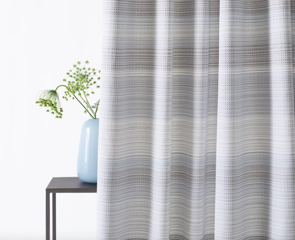 Privacy curtains in grey/white with subtle dotted pattern next to plant in blue vase