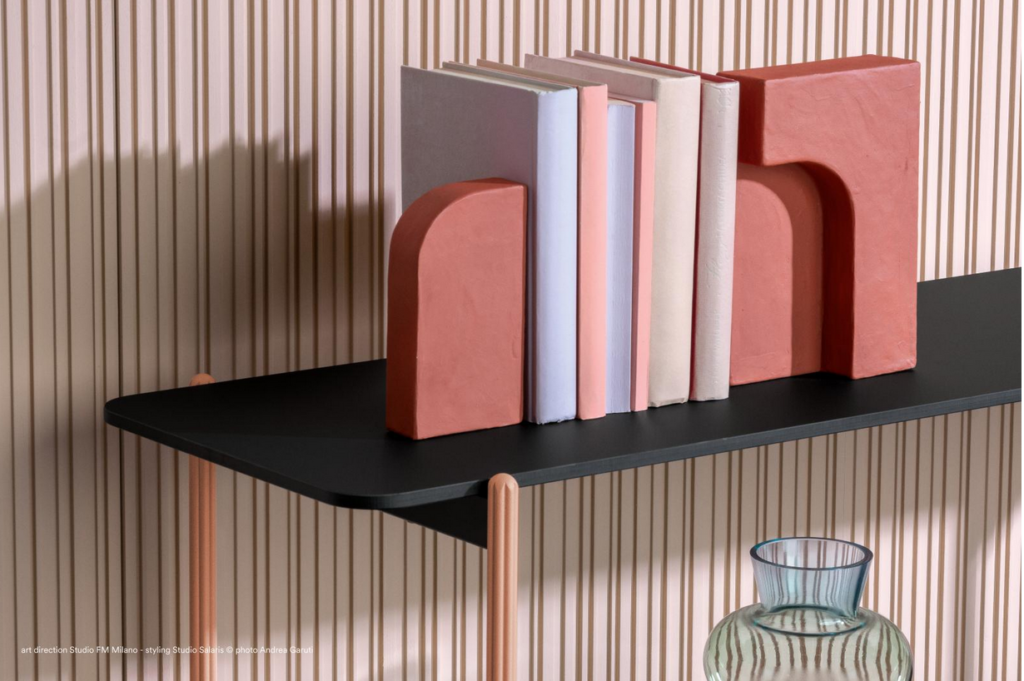 Shelving unit detail with pastel-colored books atop black shelf