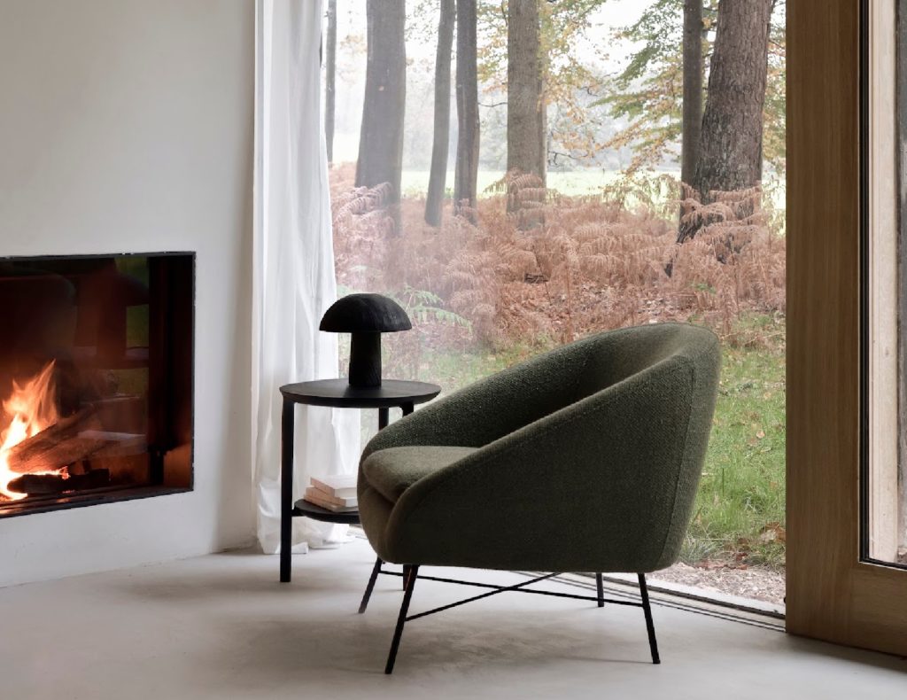 Green lounge chair near fire with forest scene visible outdoors