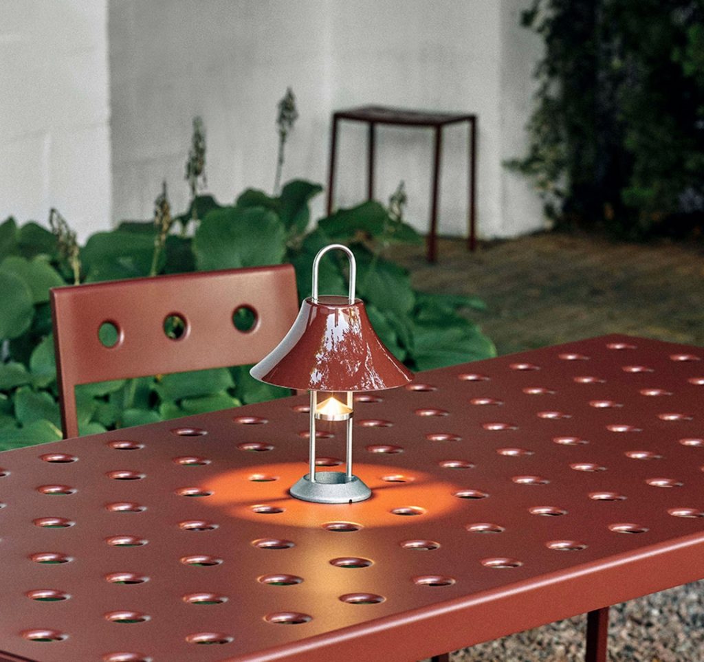  a red stainless-steel lamp on an outdoor patio table