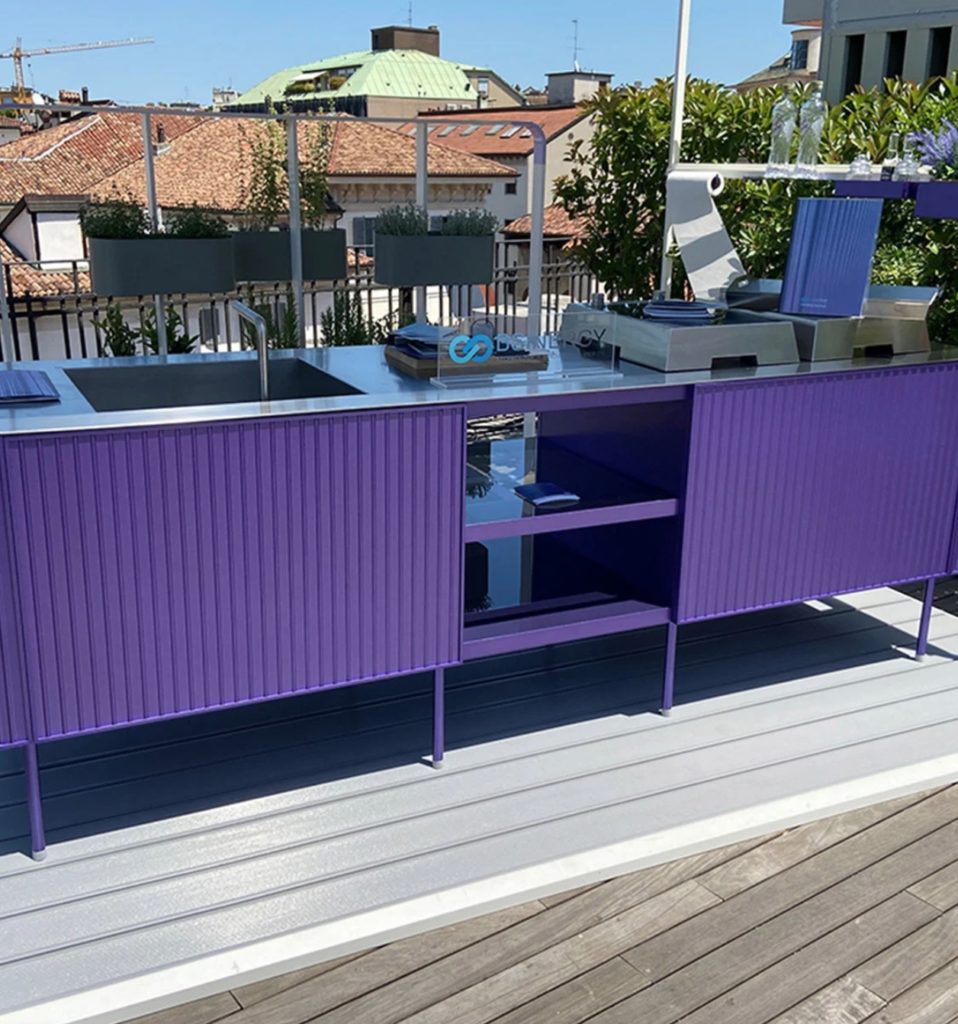 Outdoors shot of the NES outdoor kitchen in purple with tile-roofed houses in the distance