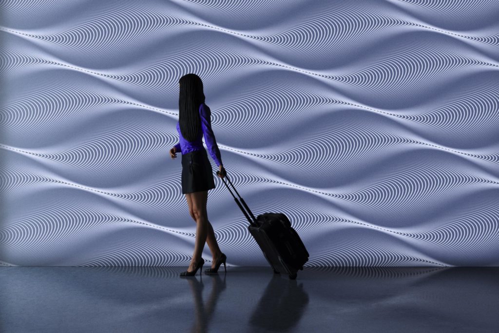 Solid surface wall with wavy texture like billowing sands in white and woman with rolling bag