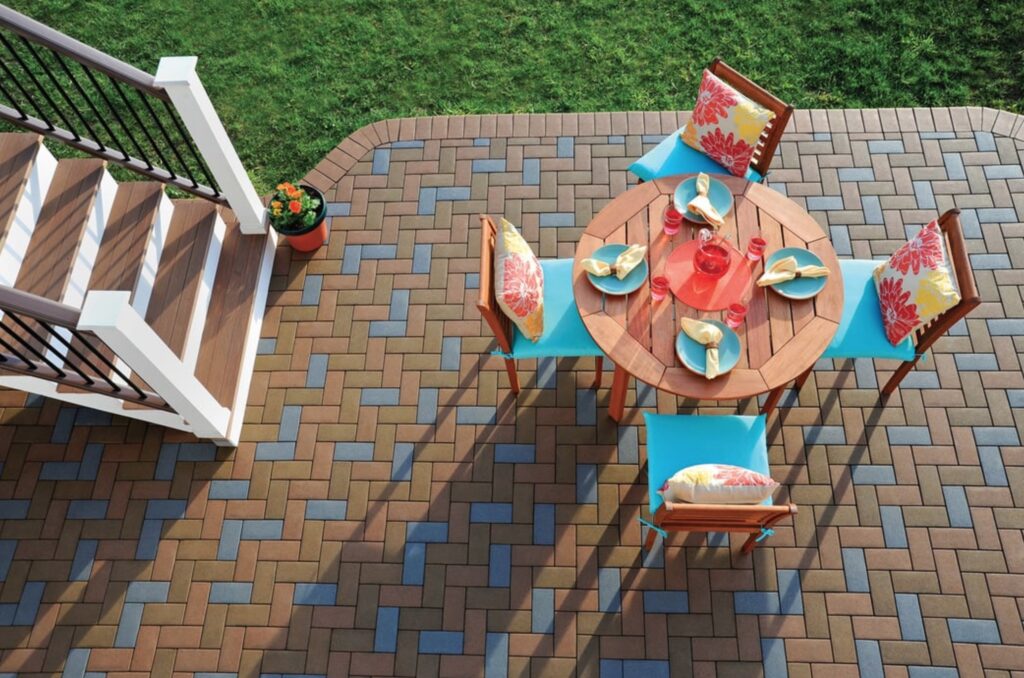 View from above in-ground pation with reddish, brownish, and blue-colored pavers and dining table