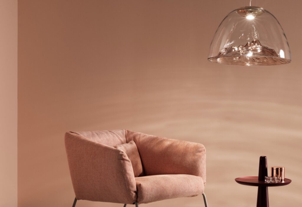 Glass pendant above lounge with peach-colored upholstery and small round table