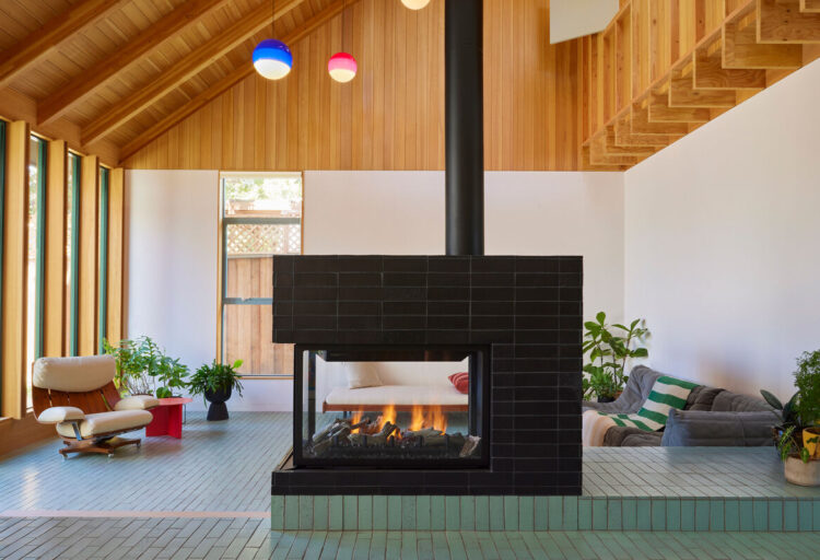 Fireclay tile black tile surrounding open fireplace in mid-century modern home with vaulted ceilings