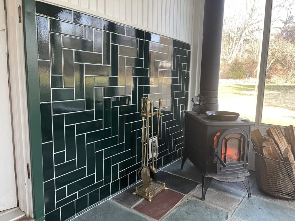 Evergreen tile in parquet style behind wood stove