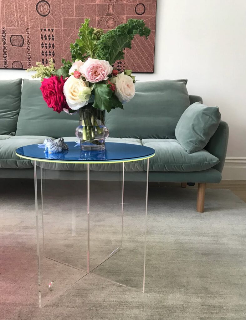 Mid Side Table with clear acrylic base and colorful top in front of comfy sofa