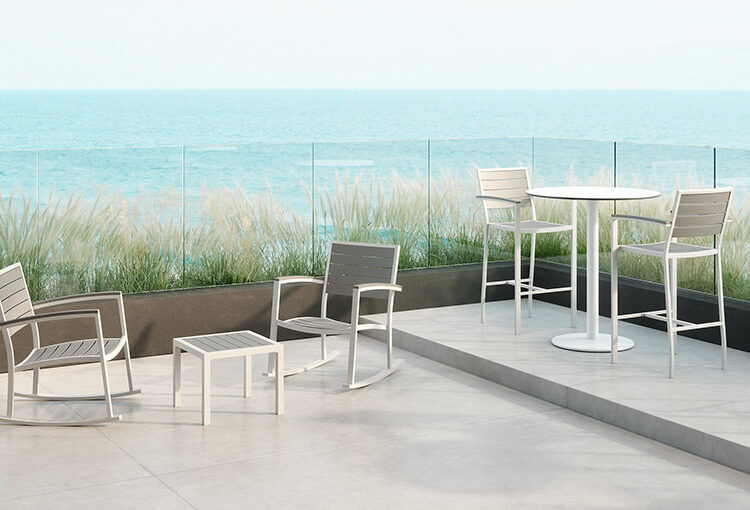 Eveleen outdoor collection side table, rocking chair, high table with stools on patio with sea view
