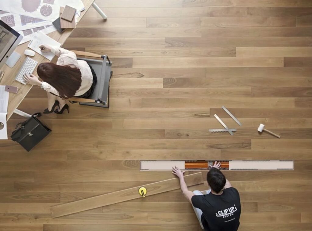 Gerbelotto floor install view from above with woman working at desk and man installing floor