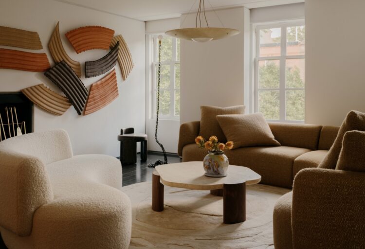Christophe Delcourt Textiles on curvy sofa in tan in comfy and eclectic room