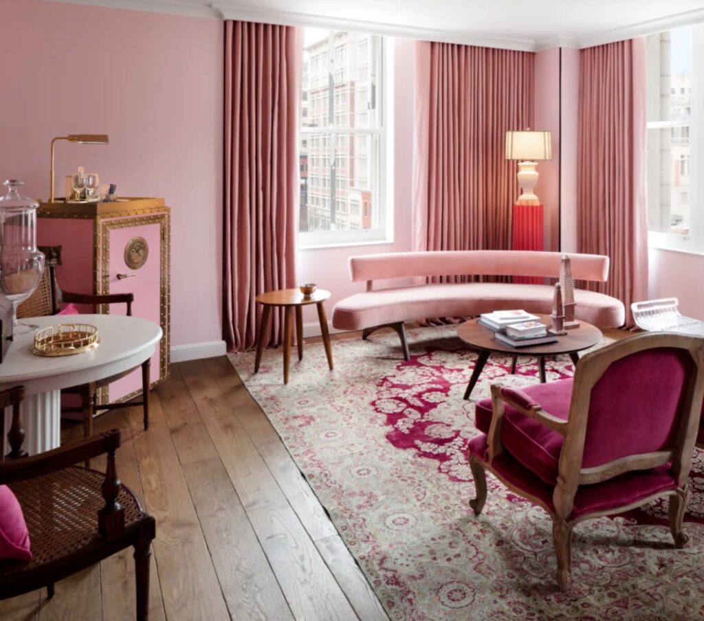 Guest suite with curved pink sofa, antique rug, and classic style wood chairs with plush upholstery