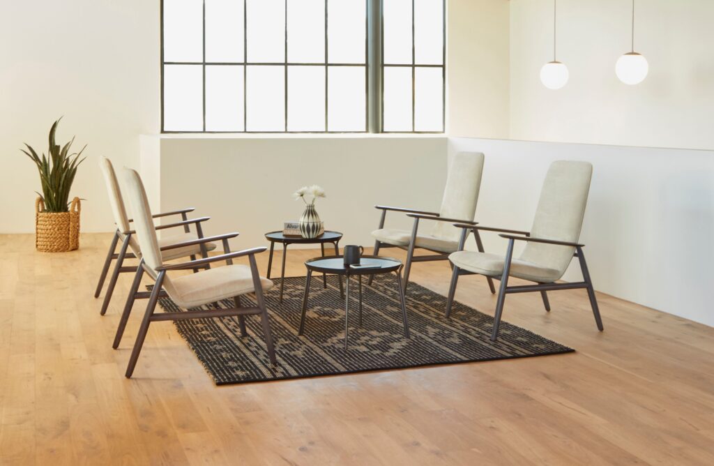 Four lounge chairs in white with coffee tables and brown rug on wood floor