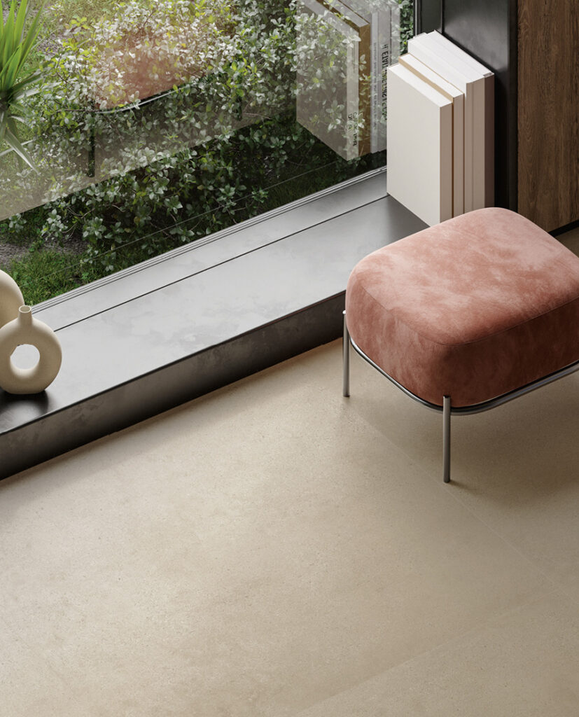 Close-up of porcelain stoneware floor in tan with ottoman upholstered in maroon fabric