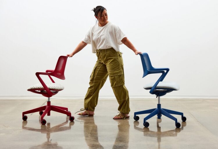Woman rolling two task chairs across the floor