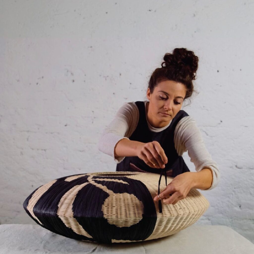 woman weaving black thread into pendant lamp shade