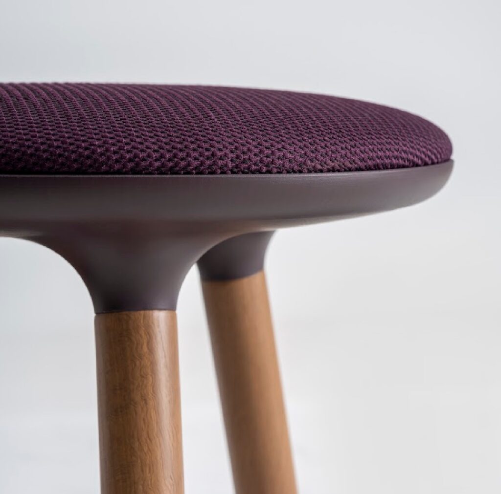 Detail of maroon fabric and metal seat on a stool