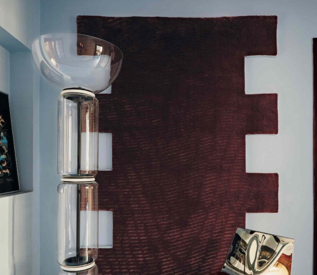 Quadratic rug on wall with glass sculpture in foreground