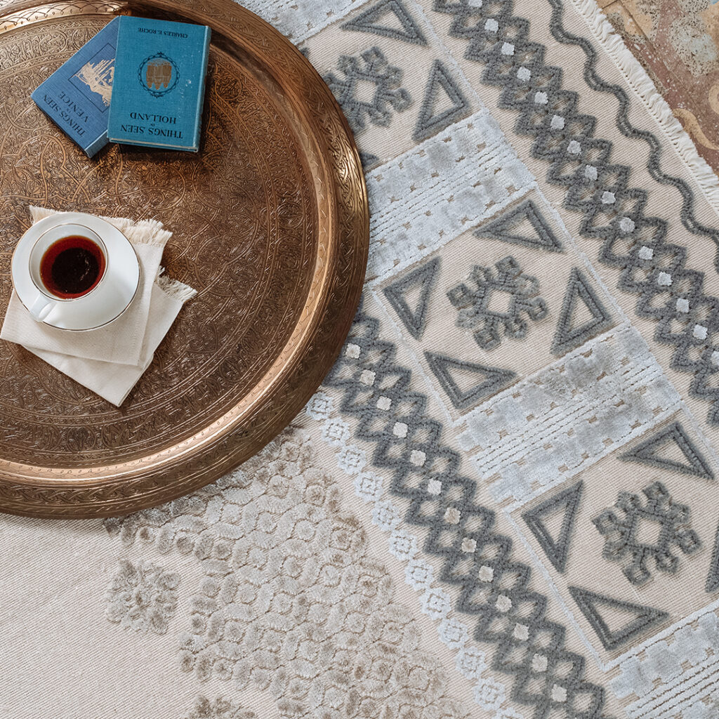 Kiliim rug detail white background with designs in gray, cream, light blue