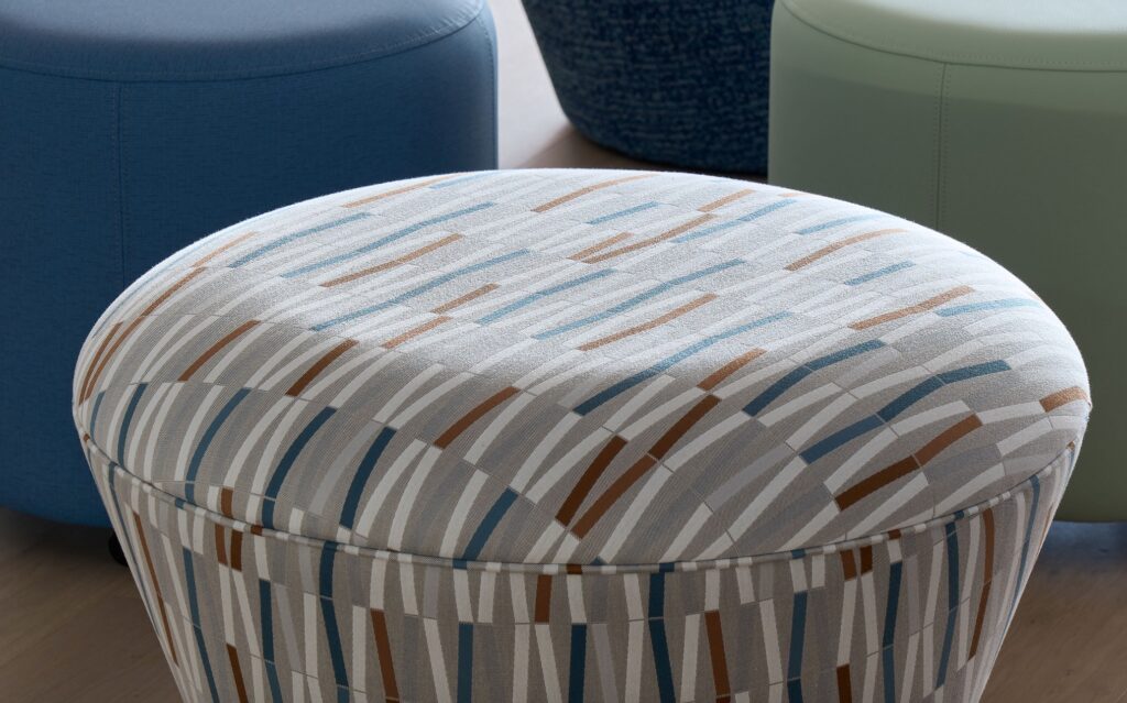 Expression fabric of wavy lines on gray background shown on upholstered ottoman