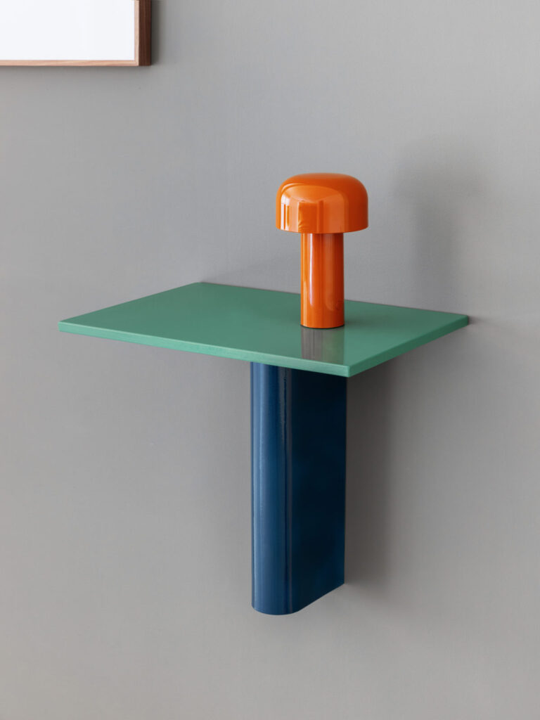 Table in blue and green with orange lamp mounted on wall