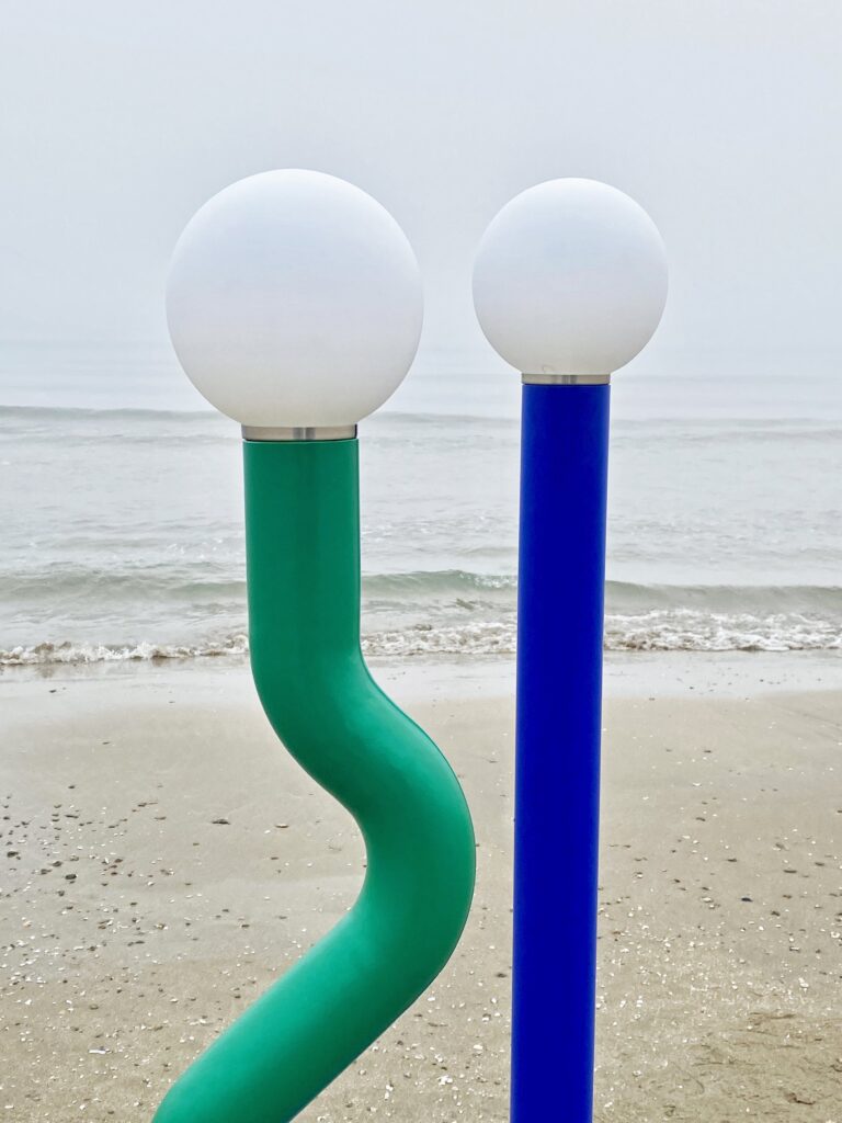 Green curvy lamp and blue straight one on the beach