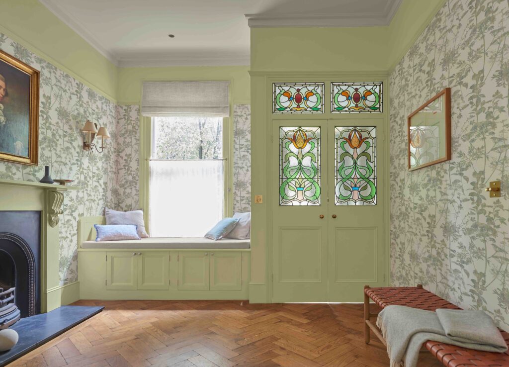 Esther in green in delightful room with doors with stained glass windows and built-in window seat