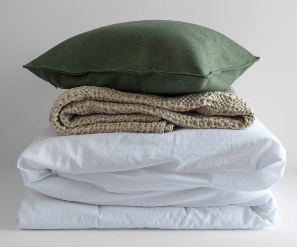 green pillow, tan blanket, and white sheet set