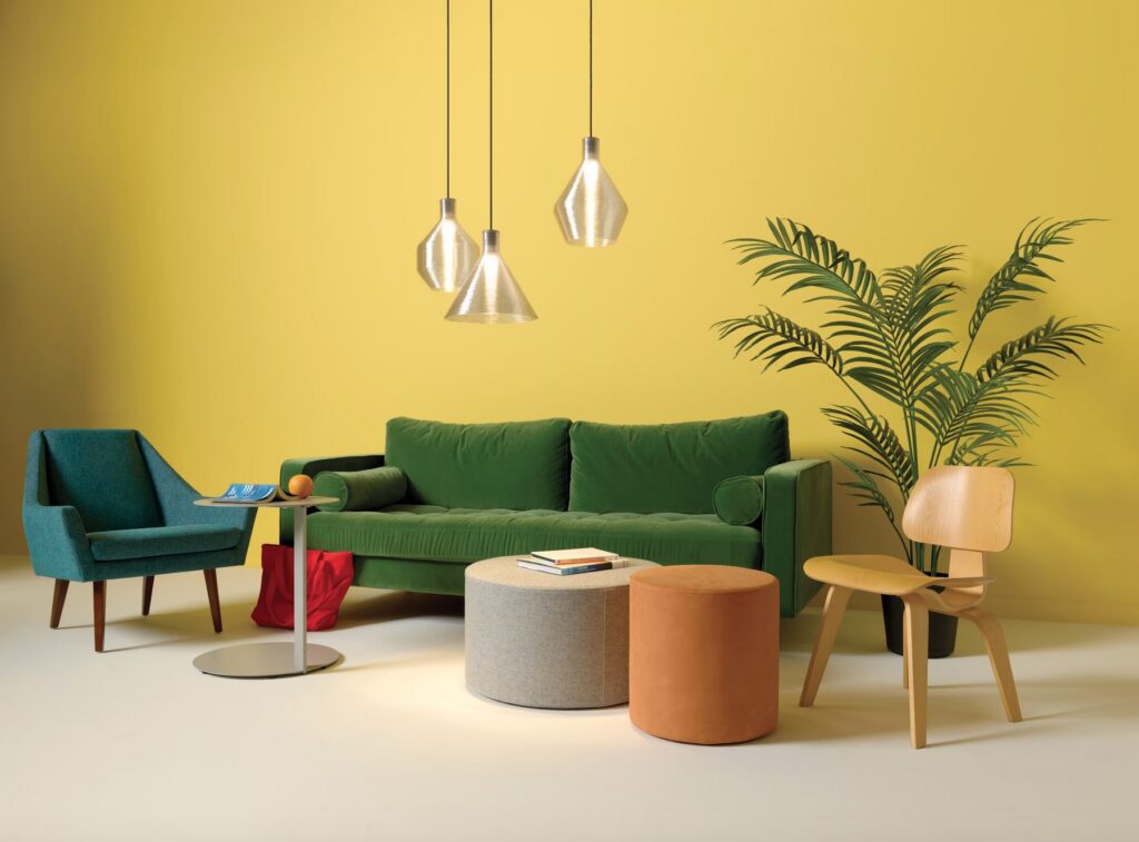 Three transparent recycled pendants in yellow room with green couch and blue chair