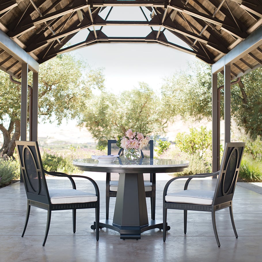 Circular dining table with two armchairs and one side chair under a gazebo