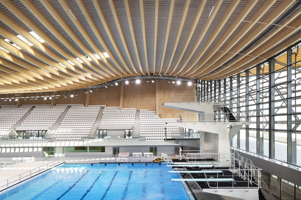 Aquatics center view of swooping roof with pool and diving boards below