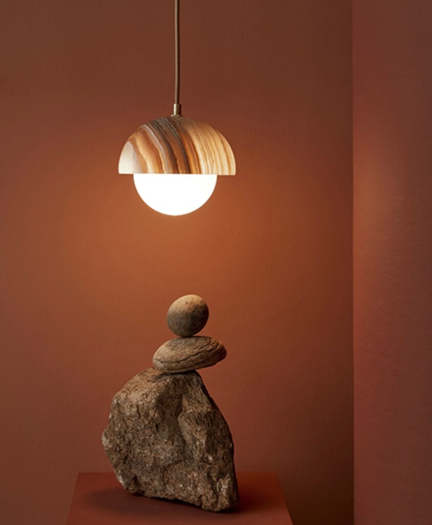 Pendant with curved shade above a balanced pile of rocks