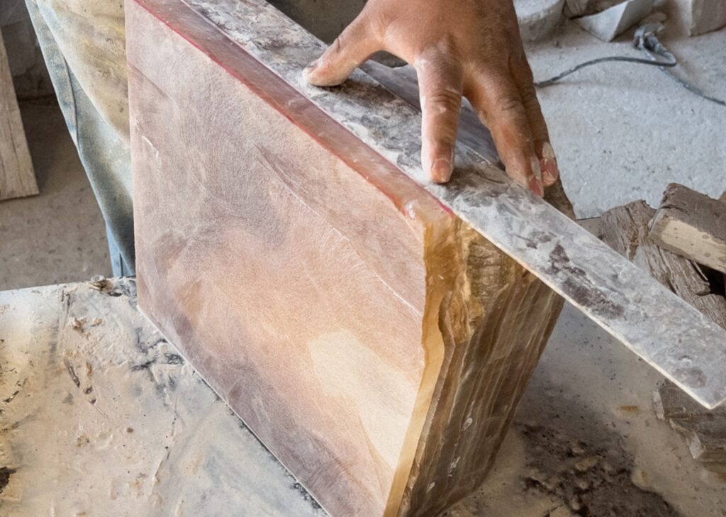 Process image with worker measuring and cutting large block of Onyx