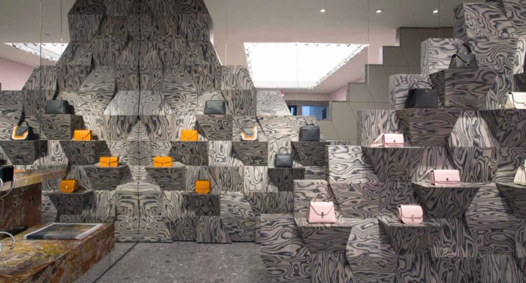 Another retail display: tower/mountain of wavy wood design with handbags displayed on niches