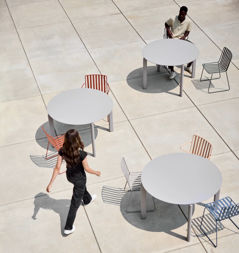 Three circular tables with man seated and woman walking view from above