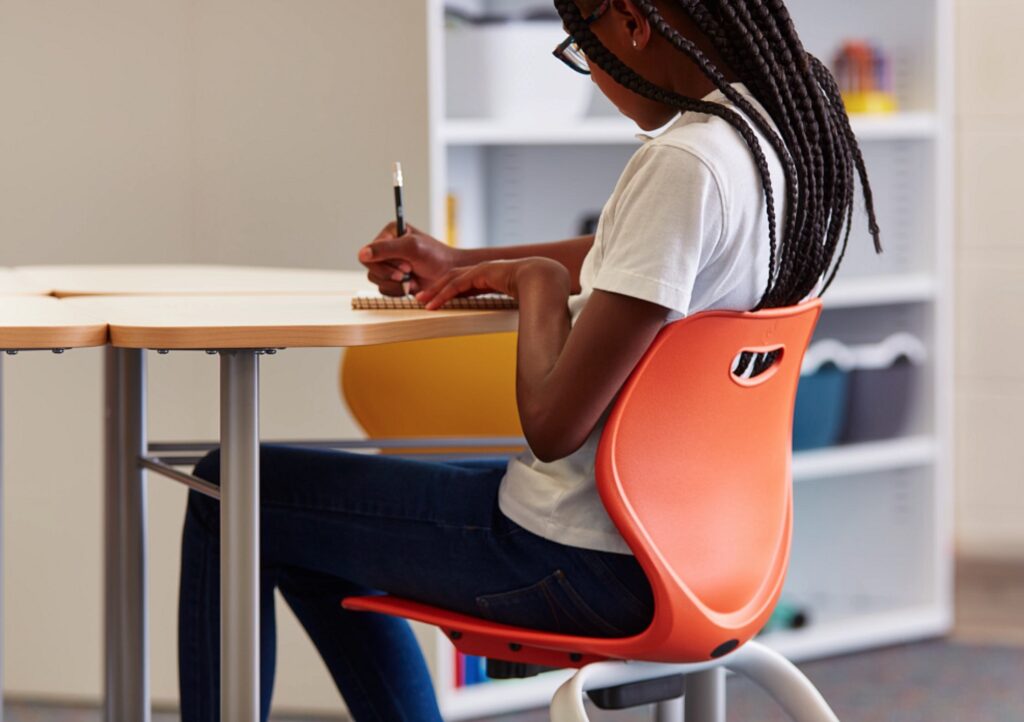 KI classroom chair in orange with girl writing 